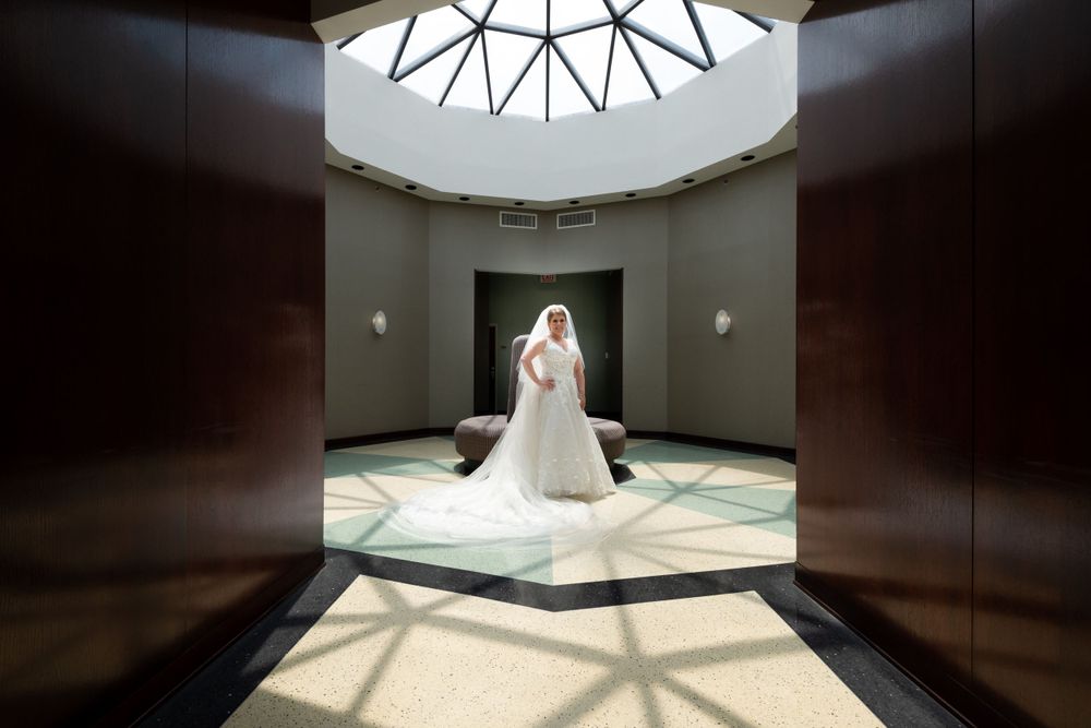 Dramatic architectural shot of a wedding venue with geometric skylight and dark walls.