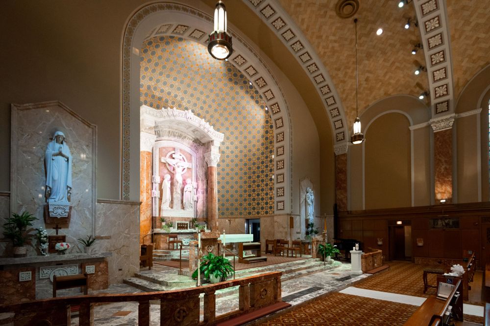 Panoramic view of a church sanctuary with vaulted ceilings and stained glass windows.