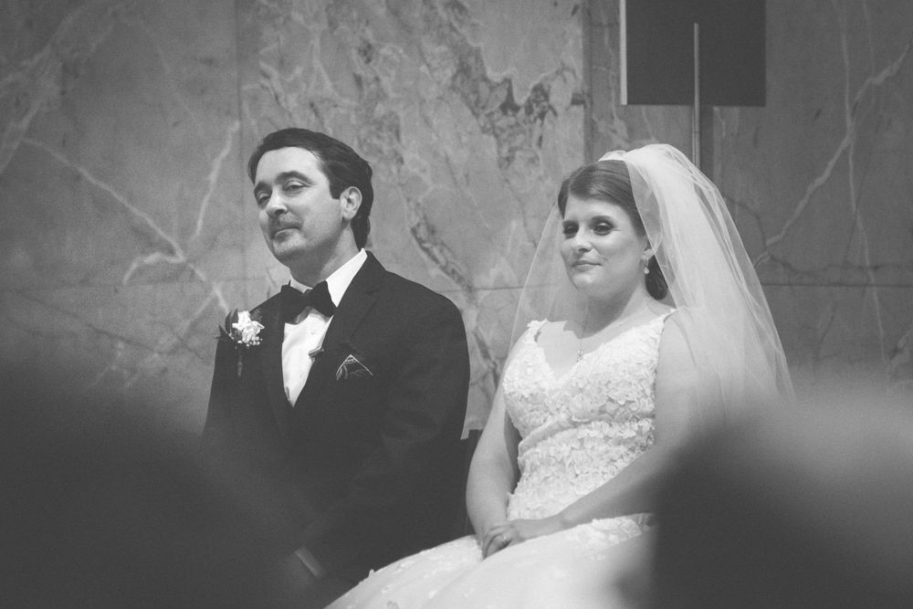 Elegant wedding couple embracing in a romantic indoor setting with dramatic lighting and shadows.