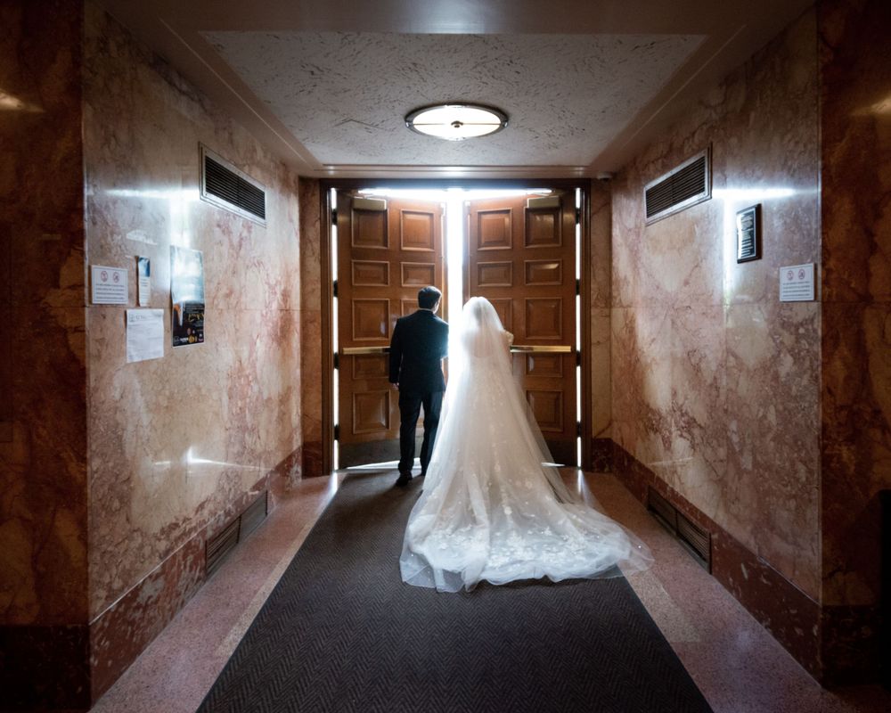Long hallway with dramatic lighting and wedding dress silhouette creating moody atmosphere.