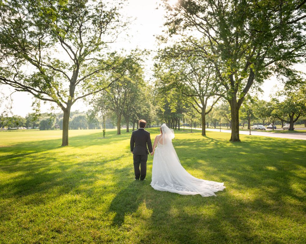 Sunlit wedding portraits in park setting with golden hour lighting through trees.