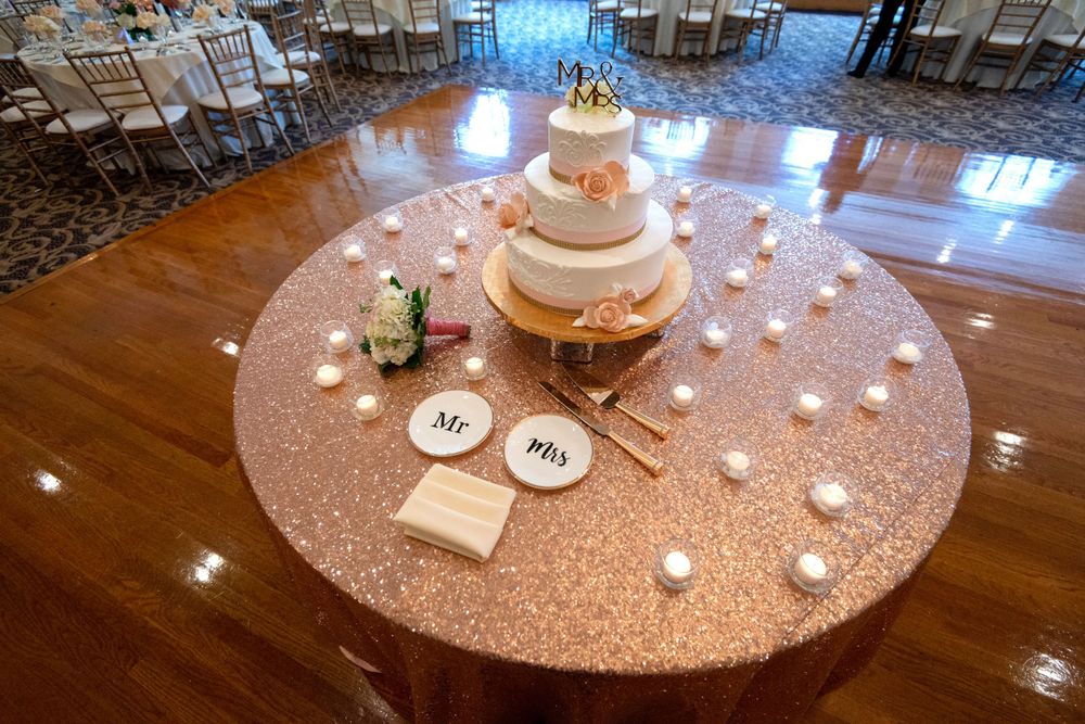 Elegant wedding reception tables with glittering gold sequin tablecloths and romantic candlelight in a ballroom.