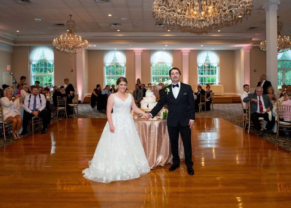 Luxurious ballroom with crystal chandeliers and pink uplighting set for an elegant wedding celebration.