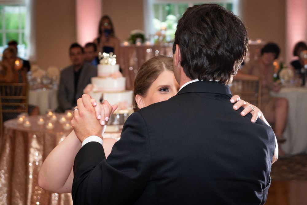 Wedding celebration in a grand ballroom with soft pink lighting and ornate chandeliers.