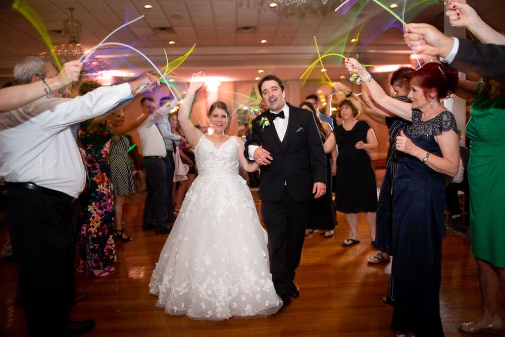 Wedding guests dancing and celebrating with glowing light wands on the dance floor.