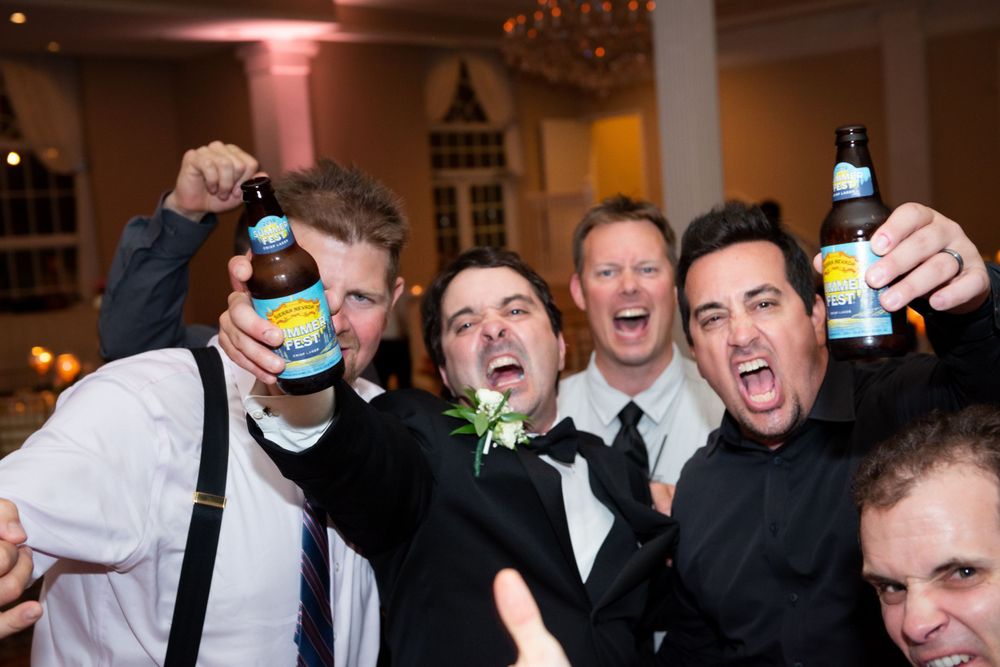 Wedding guests celebrating with drinks and laughter at an evening reception.
