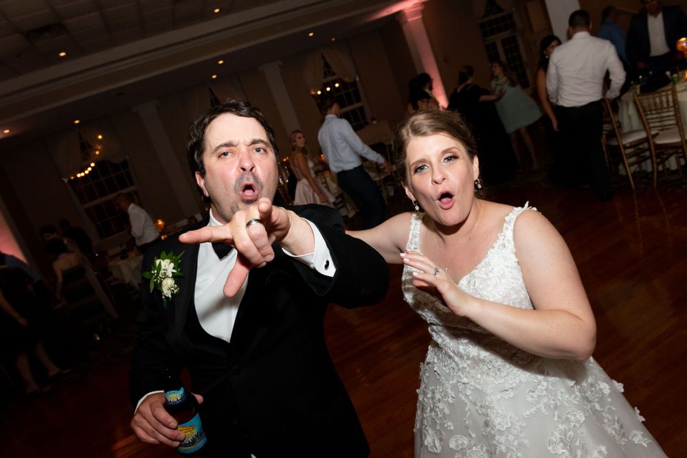 Wedding party dancing and celebrating on the dance floor during an indoor reception.