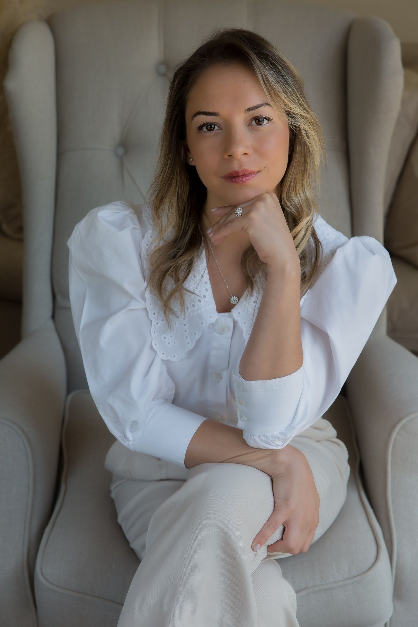 Corporate headshot of Maria Jose Jimenez sitting on a gray sofa chair by Stela McMillan Photography, Dubai.