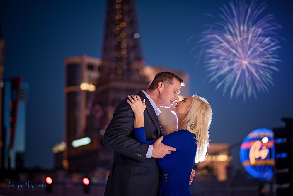 Couple sharing romantic moment with fireworks display in background at night.