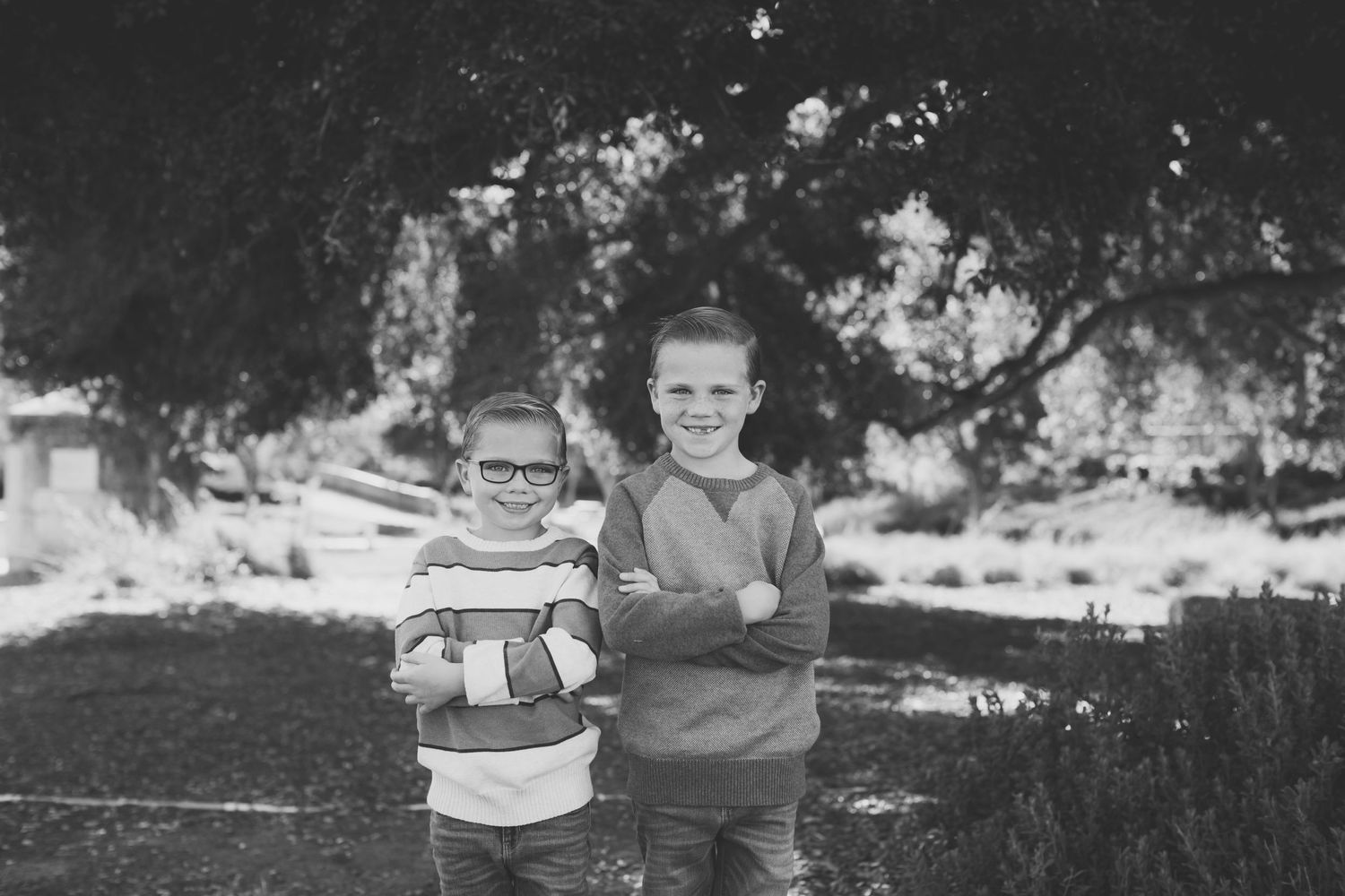 Two children standing together outdoors in a black and white portrait.