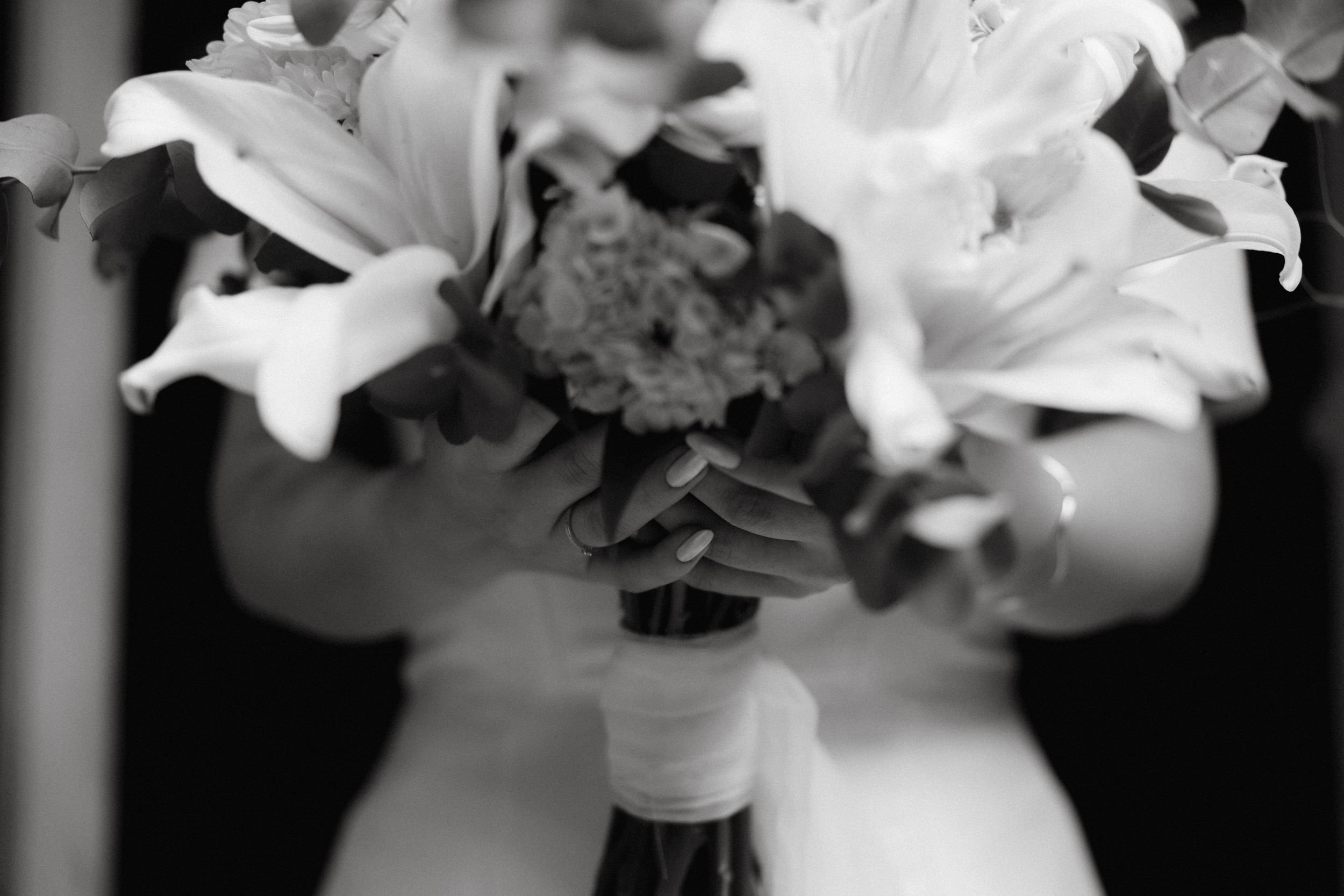Close-up black and white photo of a bridal bouquet with white lilies.