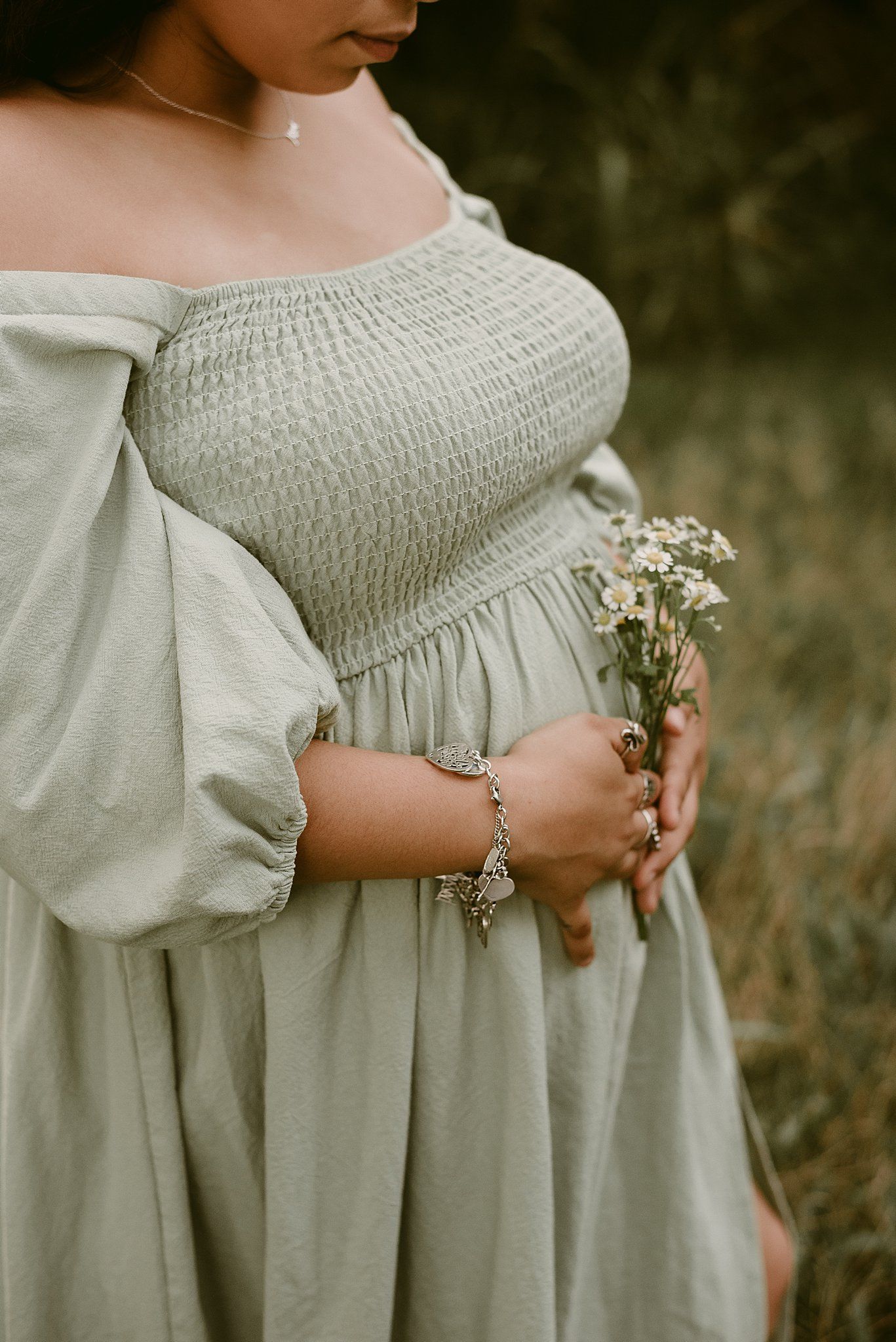 Close-up detail of a smocked bodice light gray dress with small wildflowers held against the fabric.