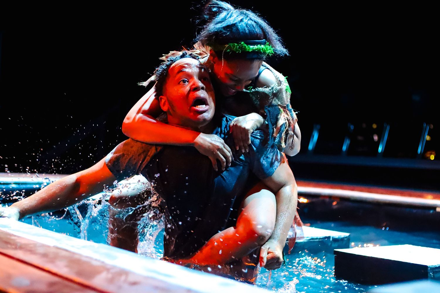 Girl dressed as a demon of hunger grasps onto the back of a boy in a pool