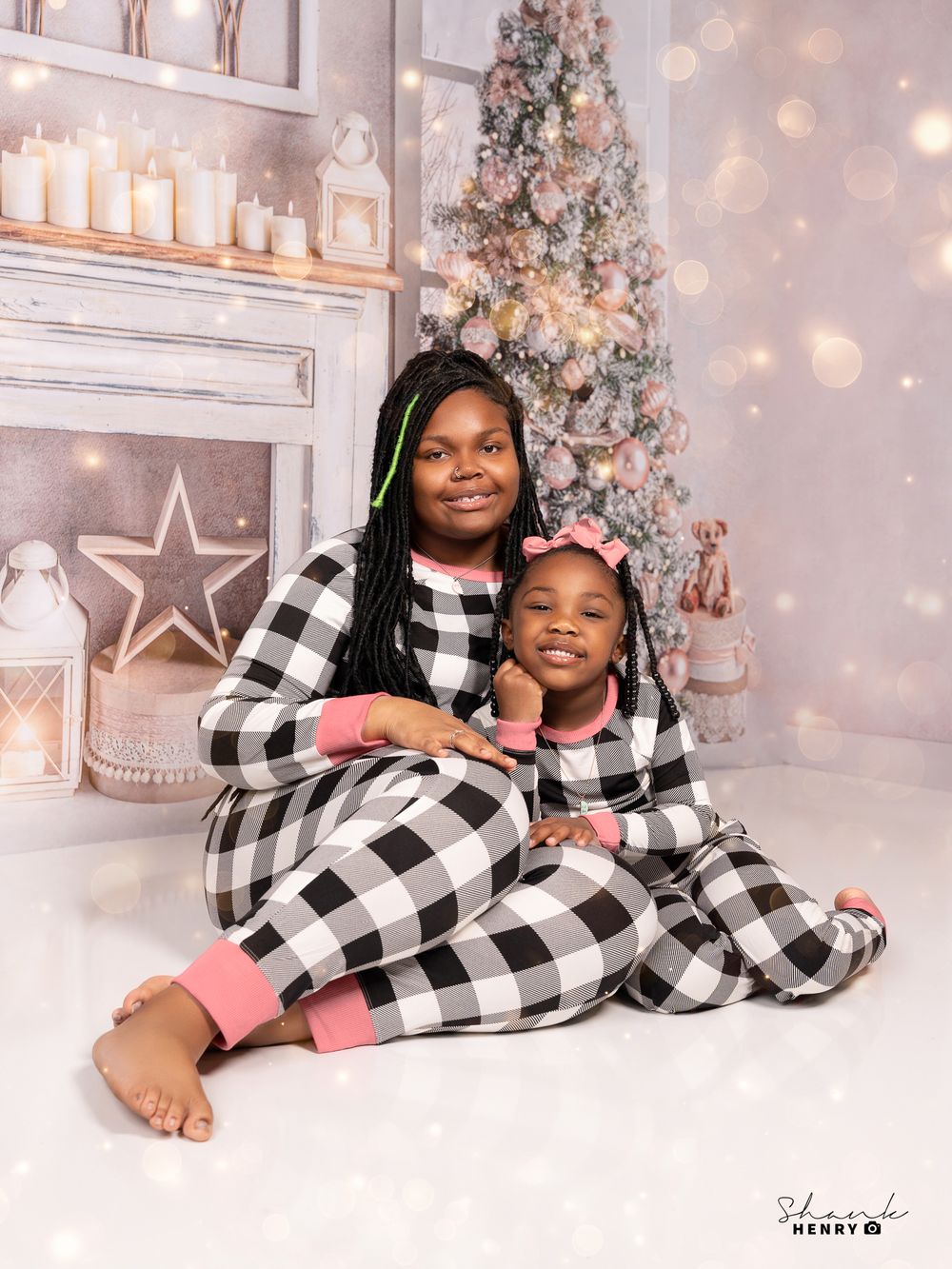 Cozy Christmas portrait with matching buffalo plaid pajamas against decorated holiday backdrop.