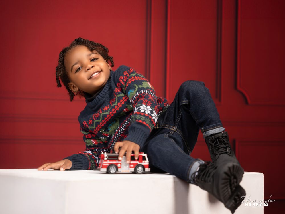 A cozy winter scene with a toy train and holiday decorations against a red background.