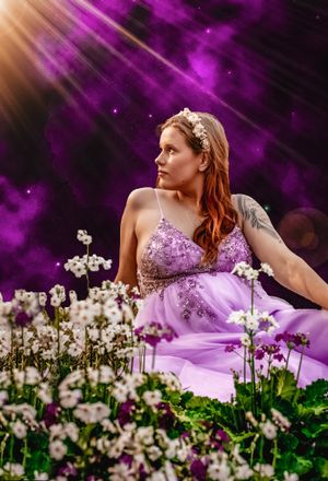 Dreamy portrait in purple lighting surrounded by white flowers.