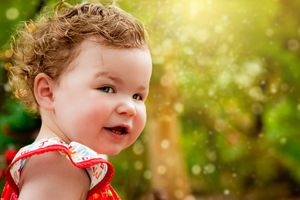 Whimsical outdoor portrait with bokeh lights and sunny natural backdrop.
