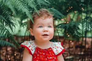 Enchanting garden portrait with ferns and magical sparkles in natural lighting.
