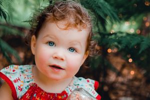 Magical forest fairy portrait with sparkles and green fern backdrop.