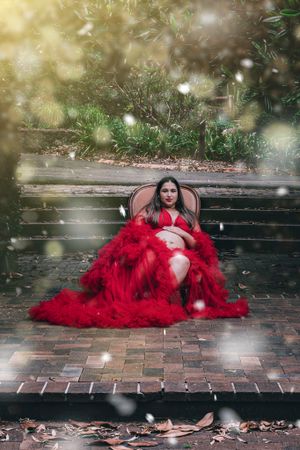 Dramatic portrait on brick path with flowing red dress and magical bokeh effects.
