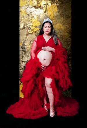 Artistic portrait against gold wall featuring dramatic red tulle dress.