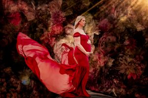 Flowing red dress creates dramatic movement in artistic autumn-toned portrait.