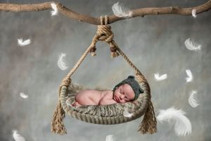 Rustic wooden swing decorated with feathers and tassels in a dreamy studio setting.
