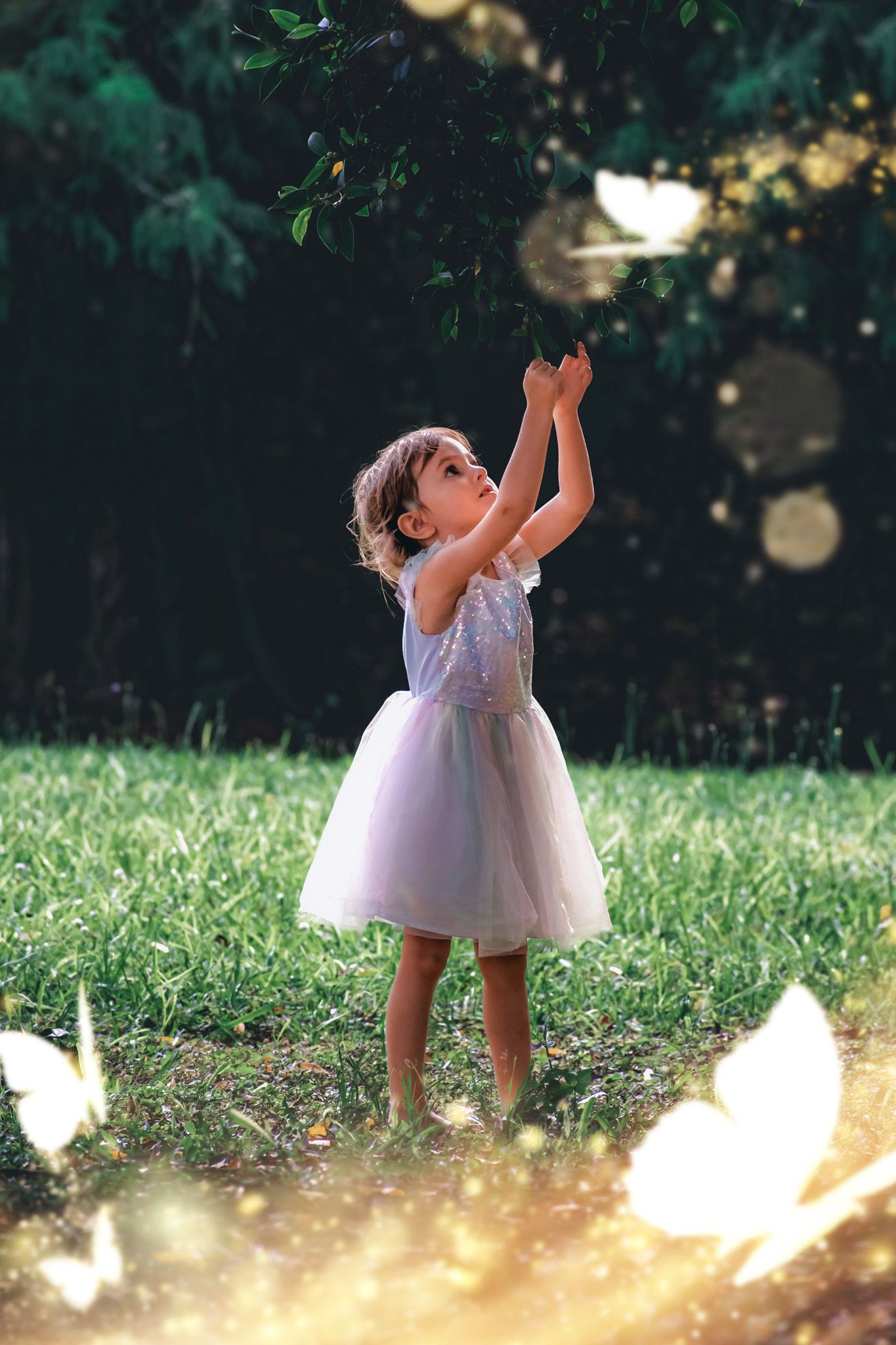 Little girl in a lavender dress twirling in sunlit garden with magical bokeh effects.