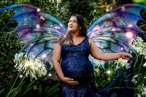 Ethereal fairy wings and sparkles create magical ambiance in outdoor maternity photoshoot.