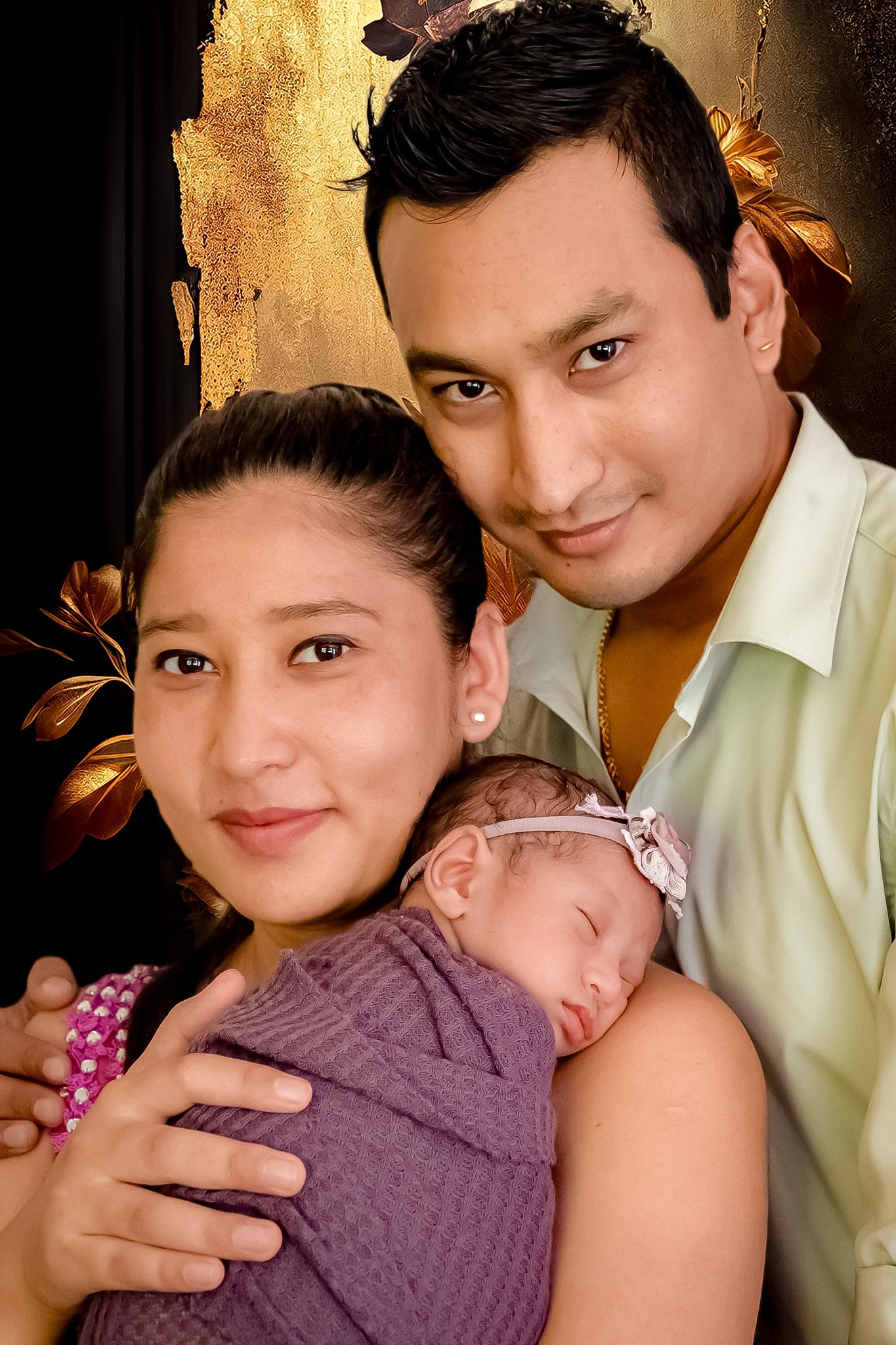 Intimate family portrait capturing tender moments with a sleeping newborn.