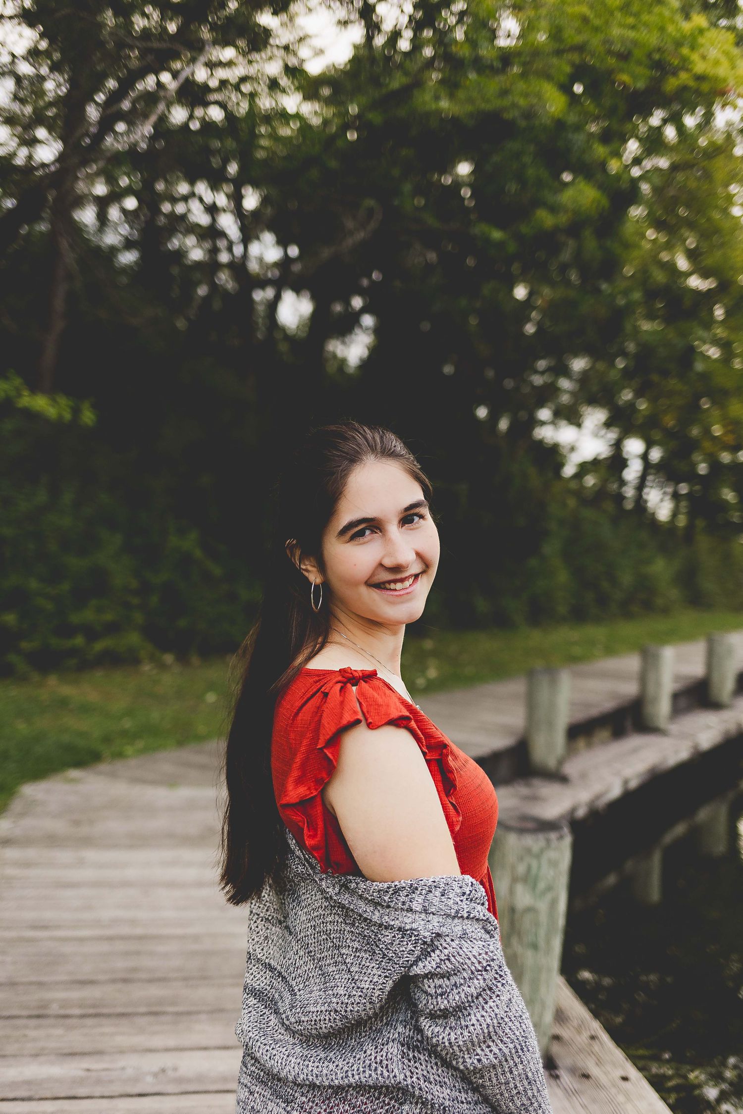 senior girl looking back at camera and smiling while on a wooden board walk in nagawaukee park delafield wi
