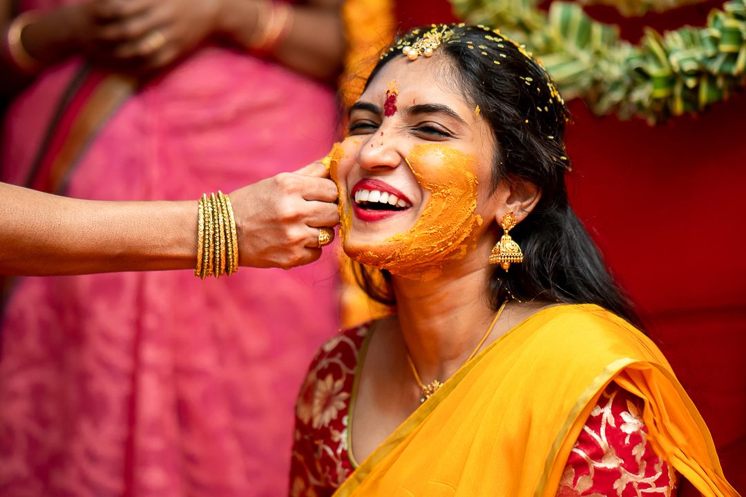 andhra bride with smiling face enjoying her haldi function while wedding photographer is capturing candid photo