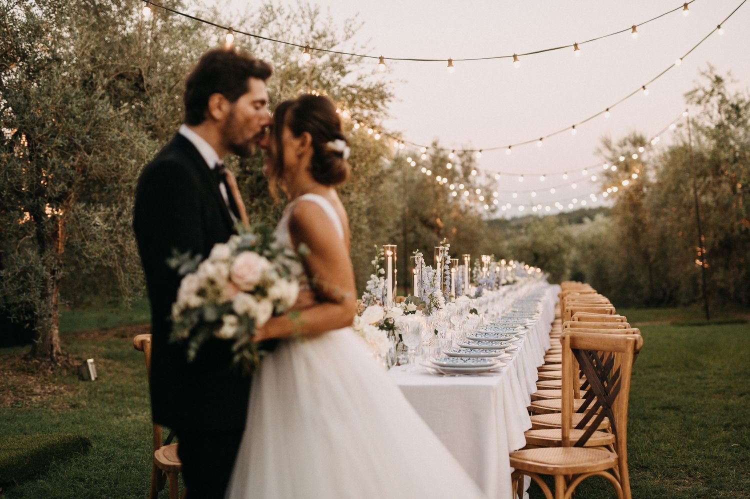Elegant outdoor wedding reception table setup with string lights and rustic decor.