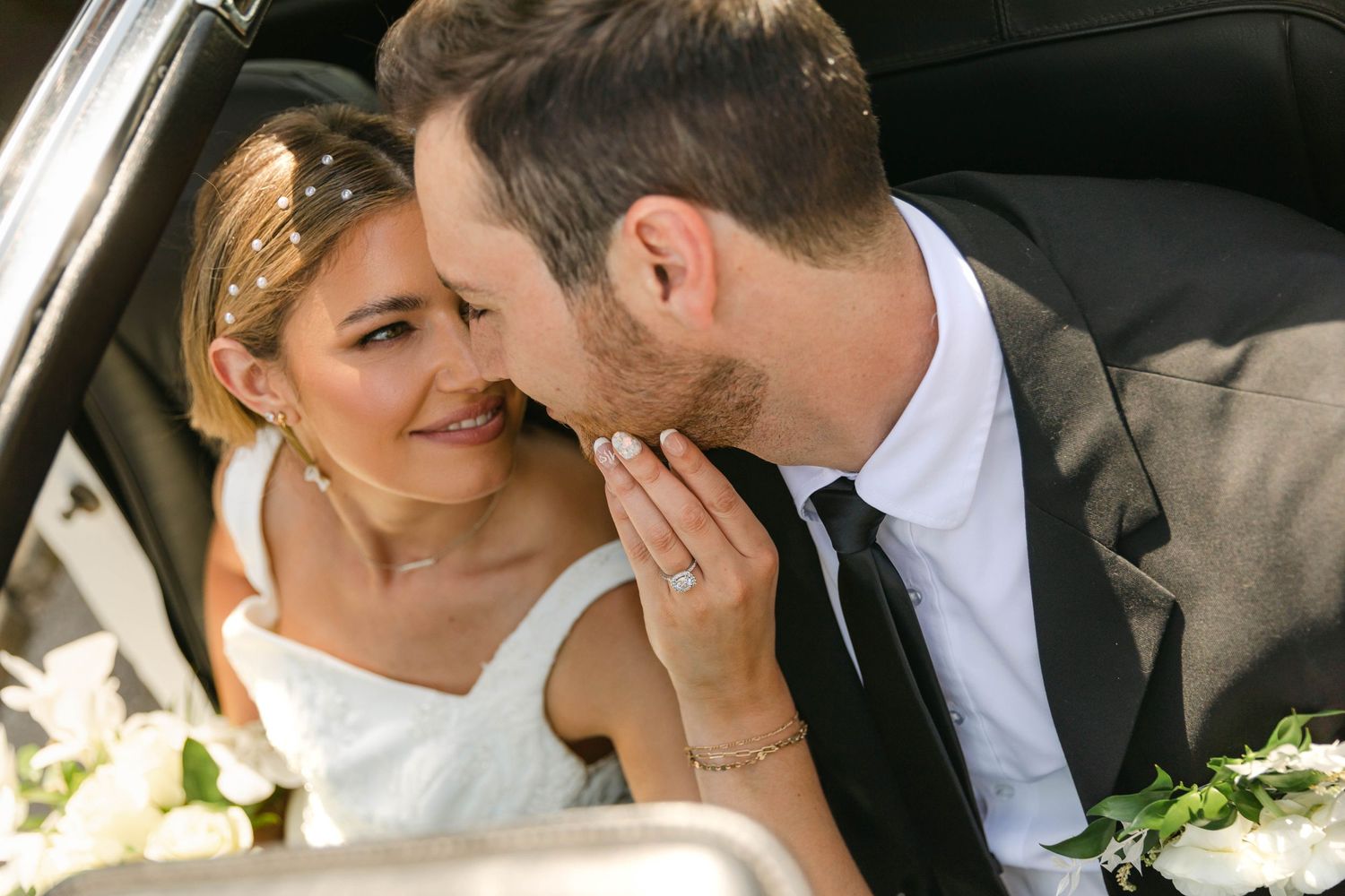 A romantic moment captured between newlyweds in a car on their wedding day.