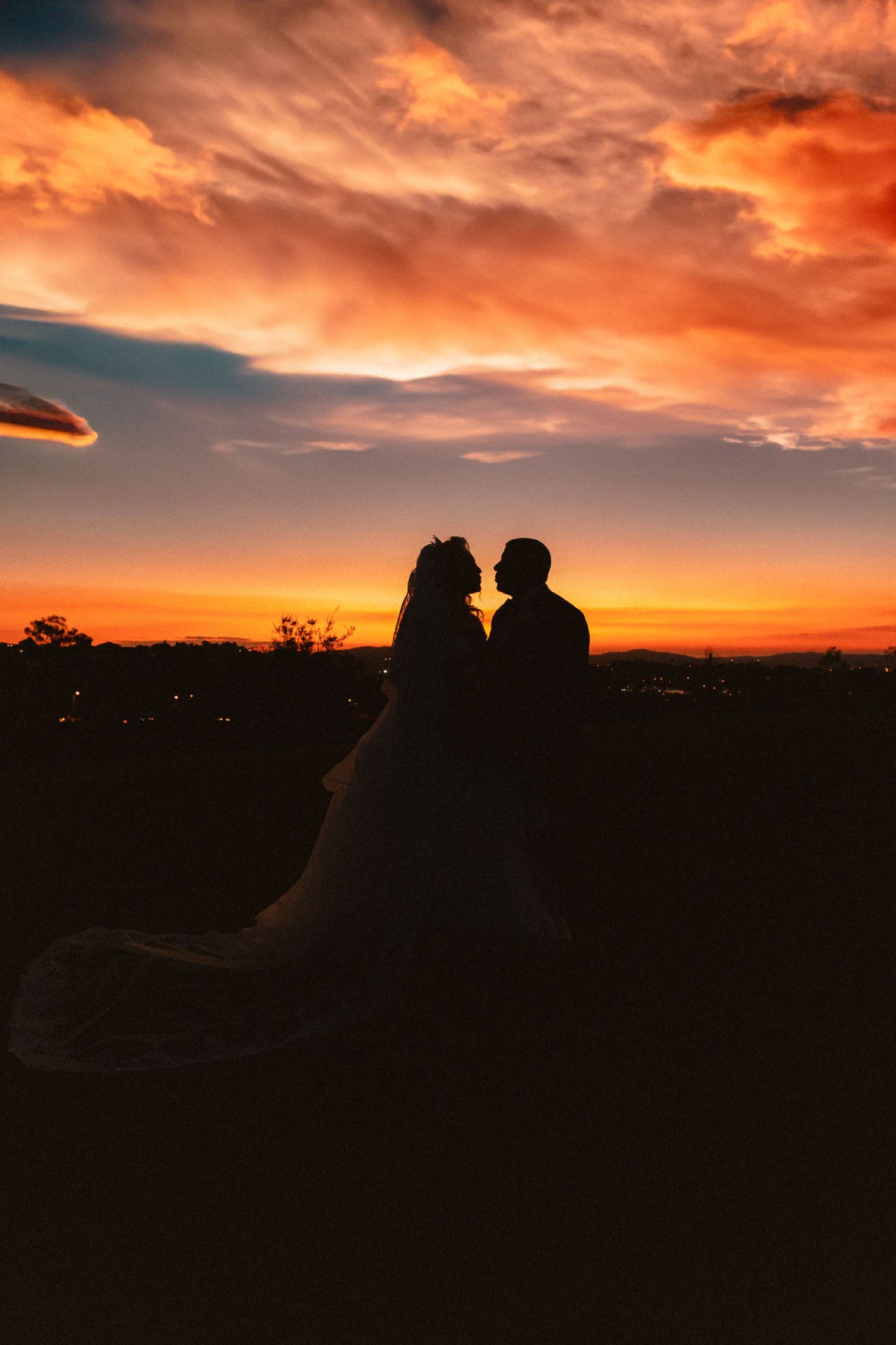 Silhouette of a couple against a dramatic orange and purple sunset sky.