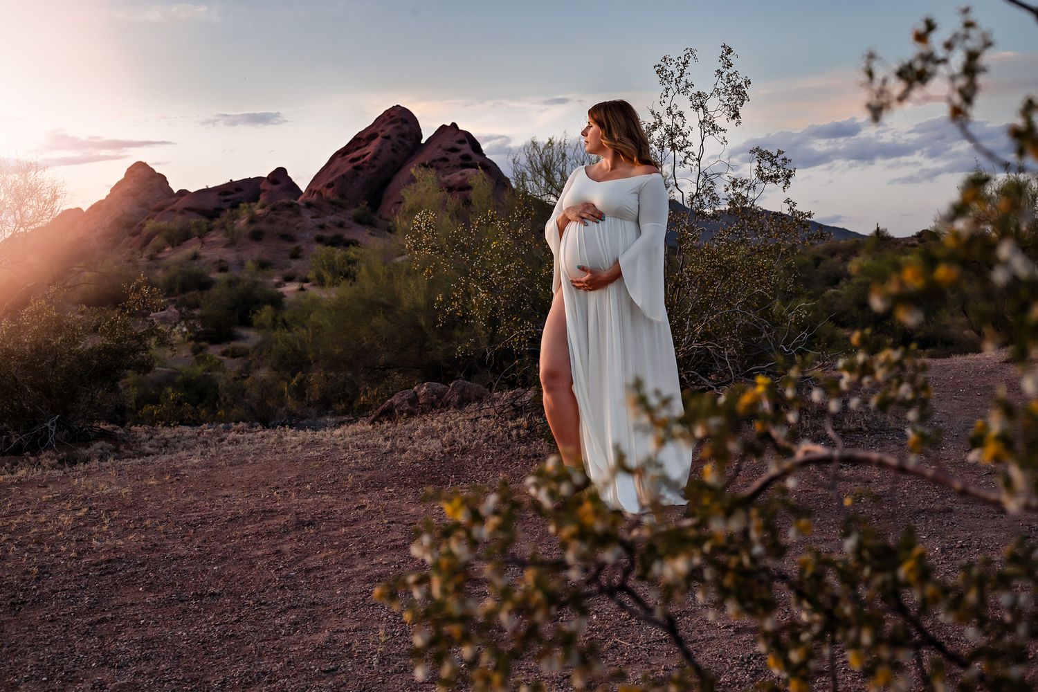 Pregnant woman looking out at the sunset in front of a beautiful mountain landscape in Arizona