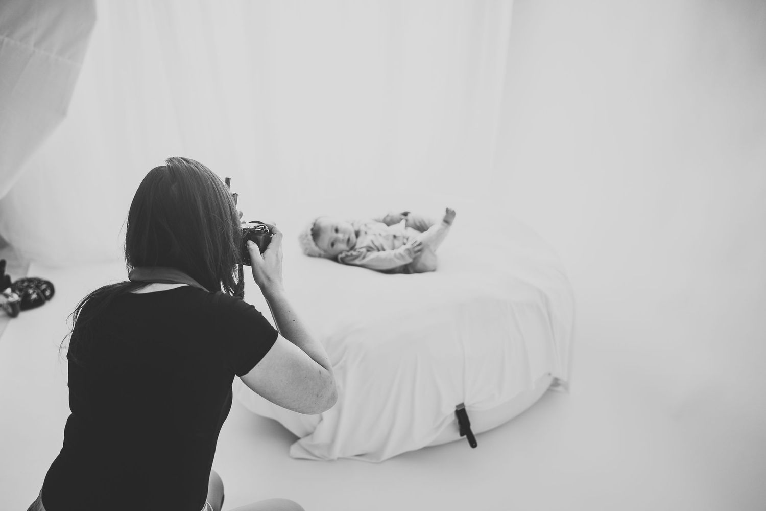 Photographer capturing a newborn session in the studio, adjusting lighting and setting up for the perfect shot – behind-the-scenes