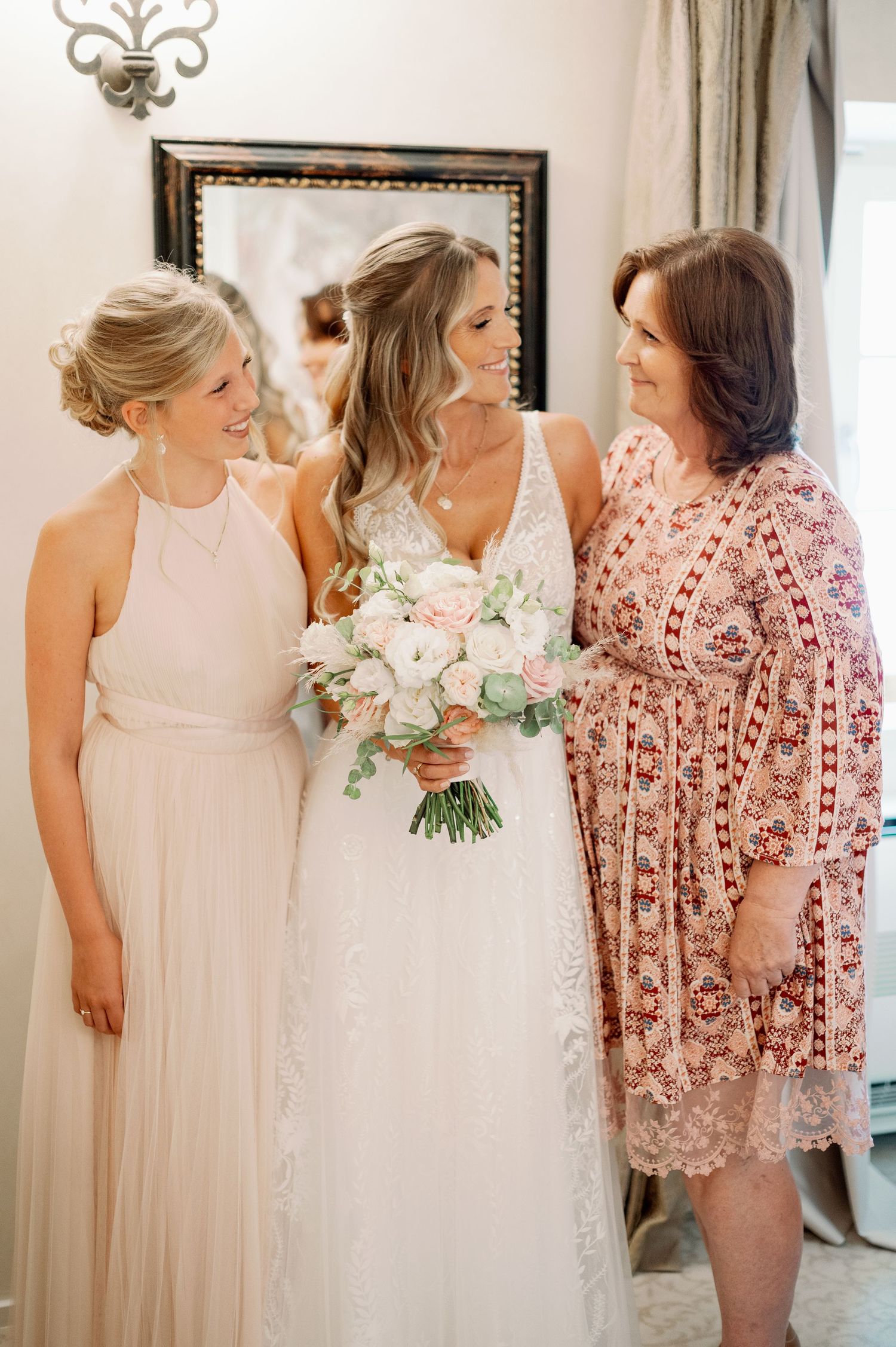 Three women share an intimate moment while getting ready for a wedding celebration.