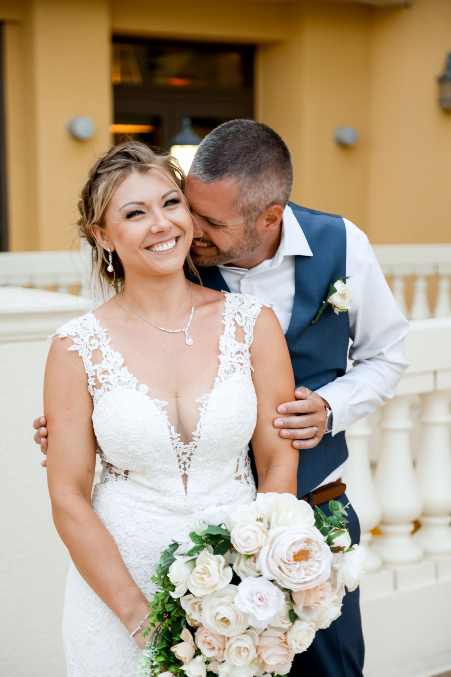 Sweet intimate moment captured between newlyweds with bride holding white rose bouquet.