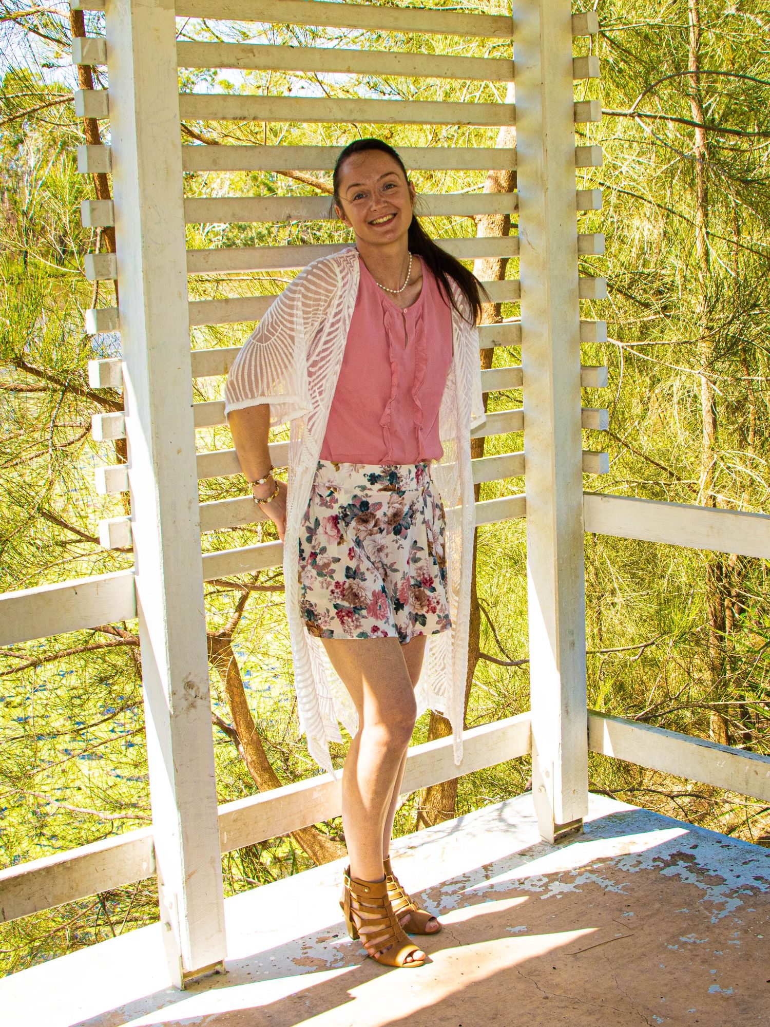 Casual summer outfit pose in a white gazebo with natural lighting and greenery.