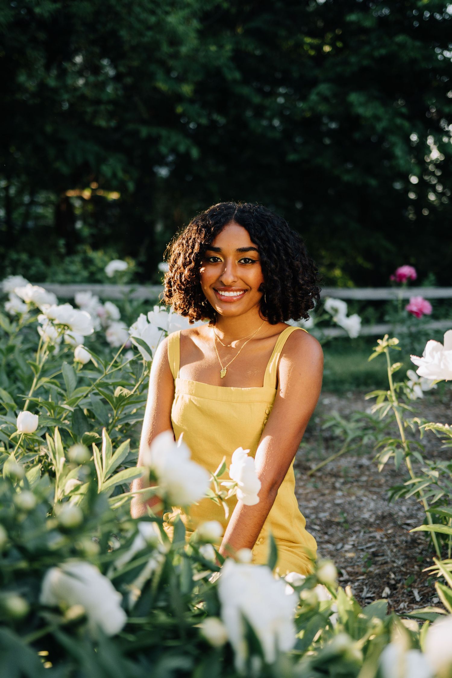 Portrait in yellow dress among blooming white flowers in a garden setting.