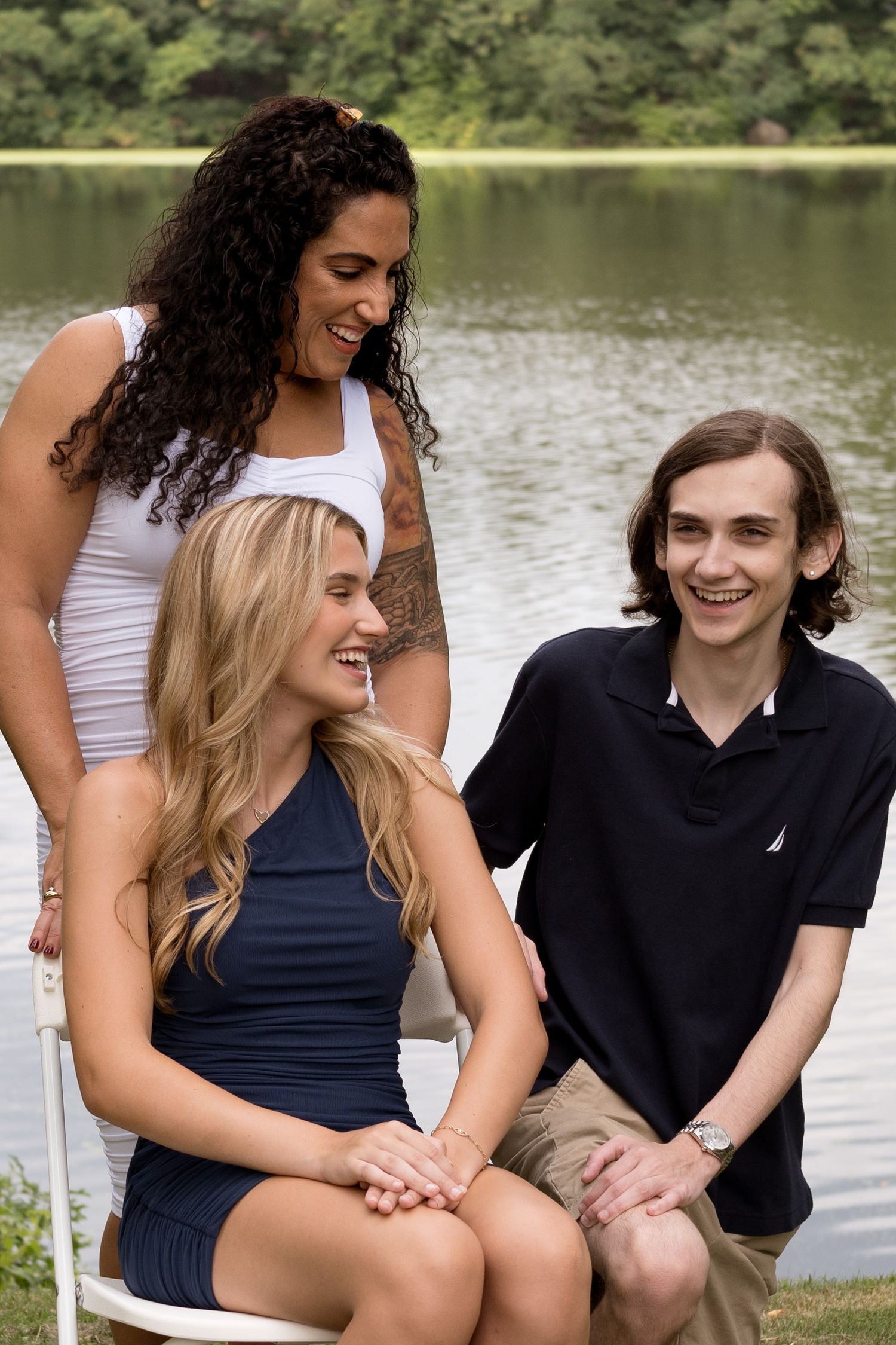 Three friends sharing a candid moment of laughter by a lakeside.