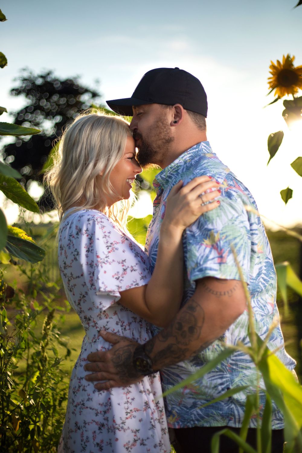 Romantic couple embracing in sunflower field during golden hour photoshoot.