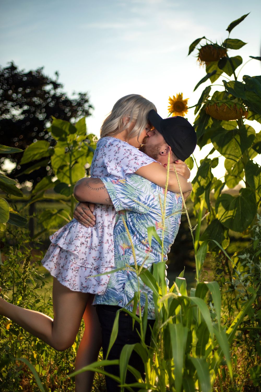 A romantic couple embraces in a sunflower field during golden hour.