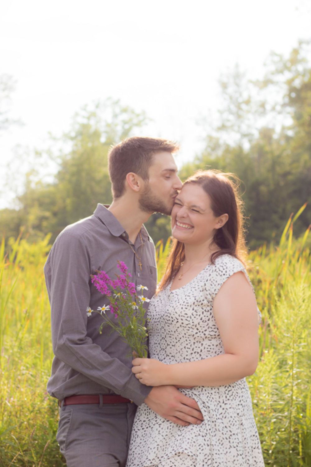 Couple shares tender moments in a sunlit wildflower field.