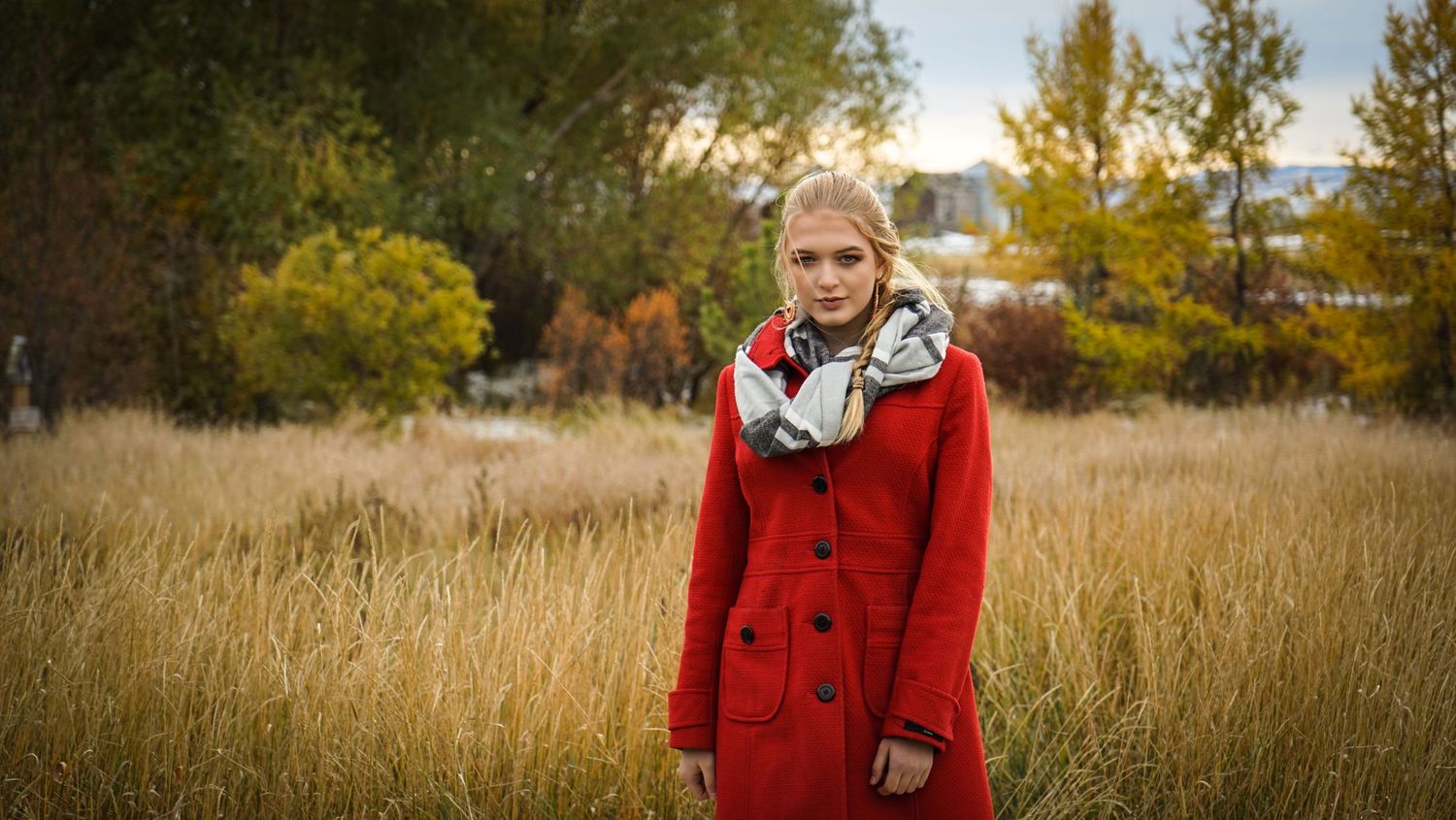 A red wool coat stands out against autumn grasses in a seasonal outdoor portrait.