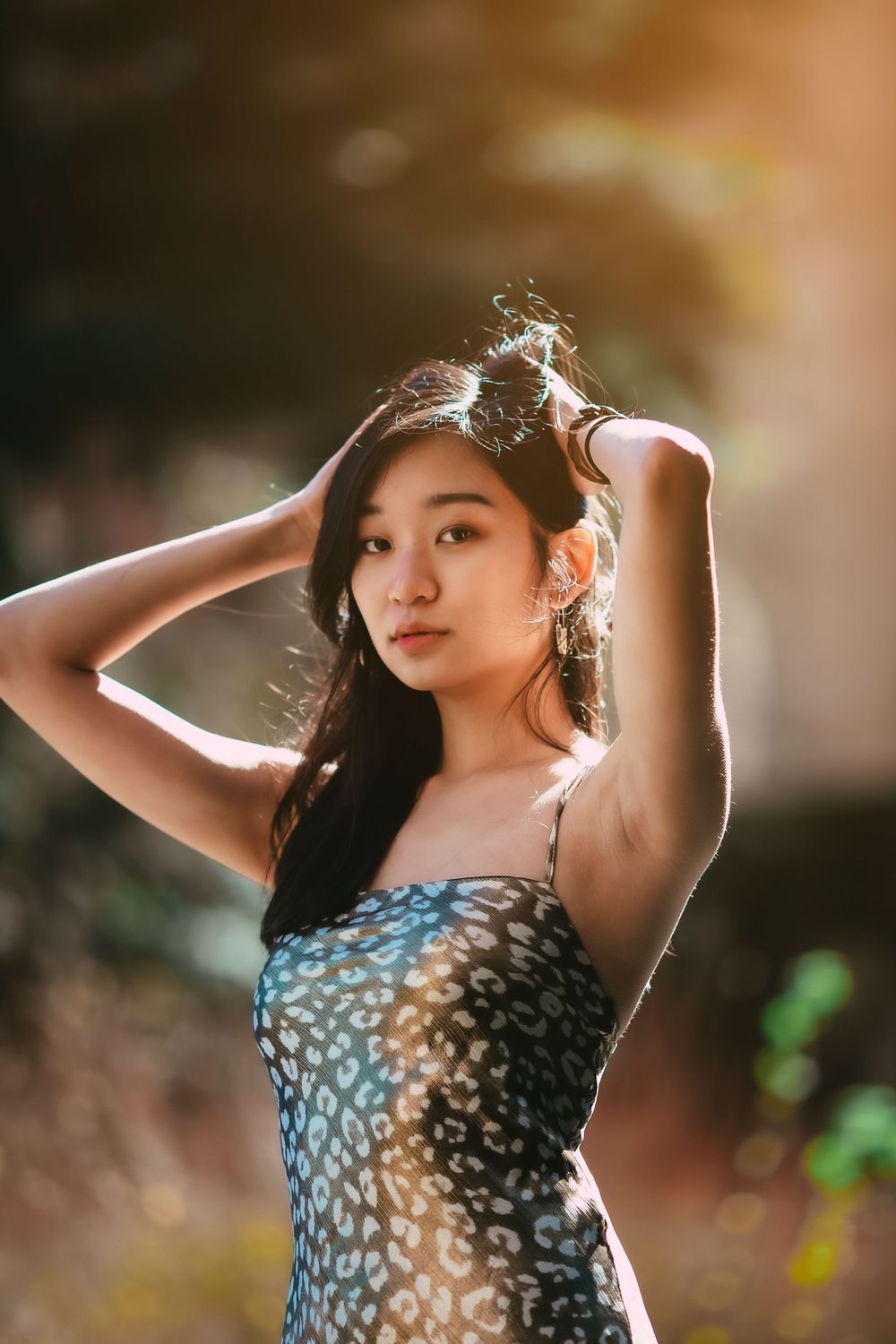 Fashion portrait of a woman in a patterned dress with sunlit backlighting.