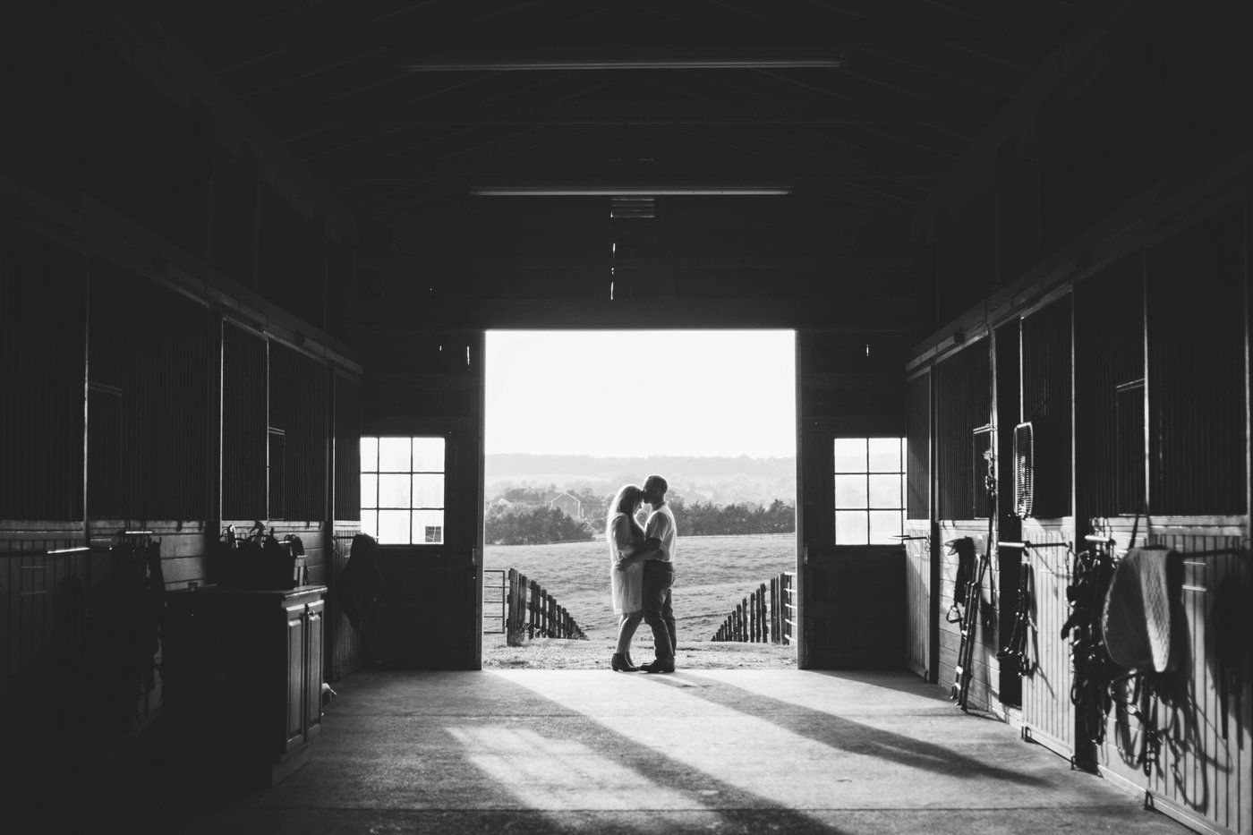 Silhouetted figures in dramatic black and white barn interior with natural light streaming in.