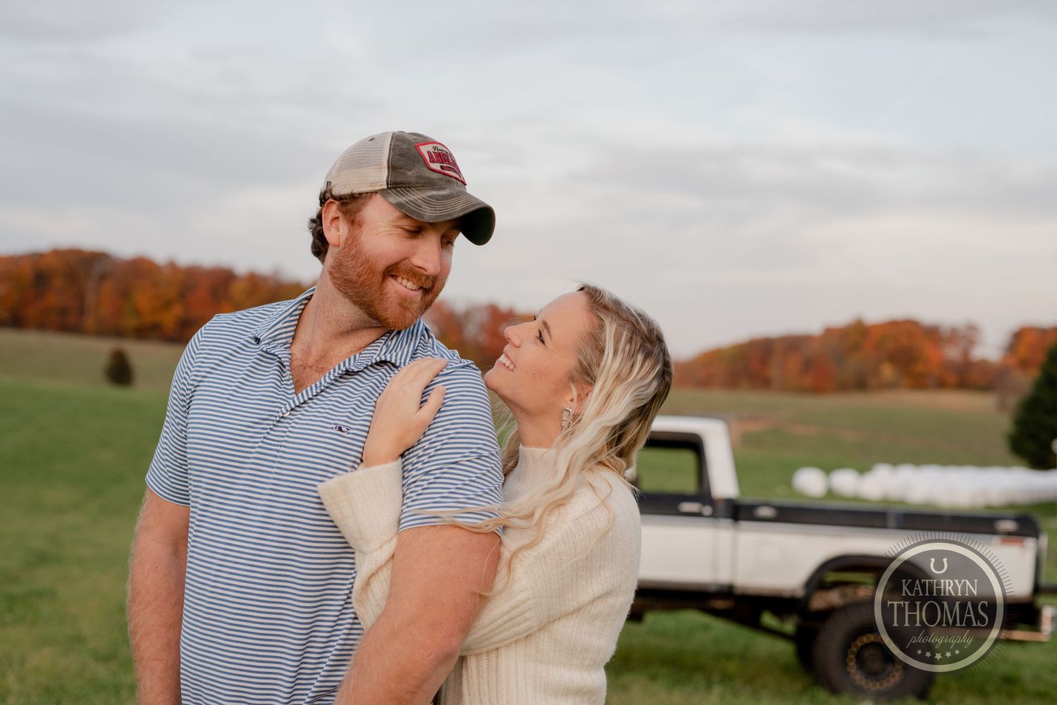 Romantic autumn engagement photo with a vintage truck and fall foliage behind the couple.