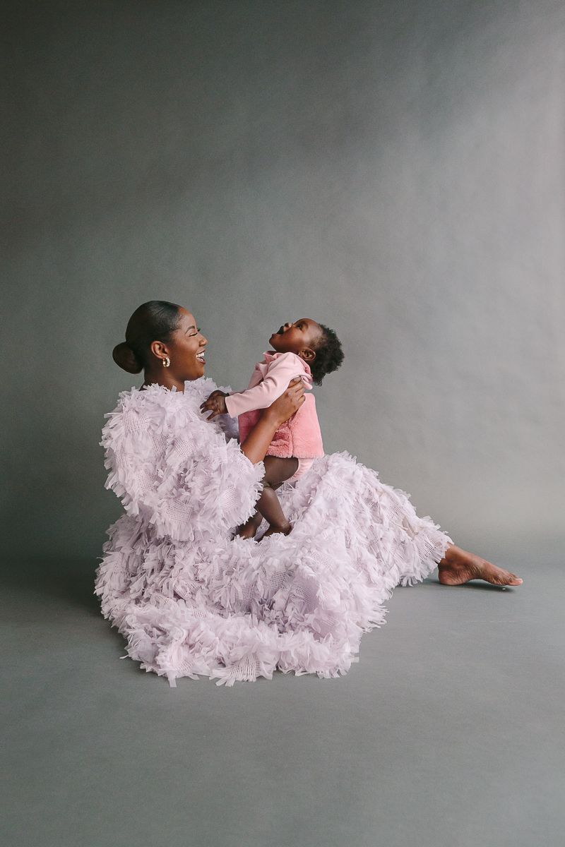 a mother and child sit on a grey backdrop during a studio session by NYC Family Photographer Paula Ortiz